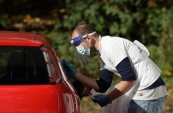 A person is tested for COVID-19 at a drive-through testing center in a car park in Chessington, Greater London, Oct. 7, 2020.