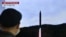 Seorang pria menonton layar televisi yang menyiarkan siaran berita uji coba rudal Korea Utara, di sebuah stasiun kereta api di Seoul pada 2 November 2022. (Foto: AFP)