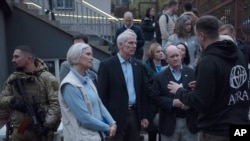 U.S. Sen. Chris Coons, centre right, and Sen. Rob Portman, centre, talk with people during their visit a distriPromising continued humanitarian s