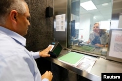 FILE - A man has his fingerprints taken electronically while taking part in a visa application demonstration at the consular section of the Embassy of the United States in Lima, Peru, October 3, 2014.