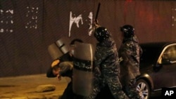 Riot police officers beat an anti-government protester during a protest near the parliament square in downtown Beirut, Lebanon, Dec. 14, 2019.