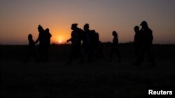 The sun rises as asylum-seeking migrant families from Honduras and El Salvador walk towards the border wall after crossing the Rio Grande River into the United States from Mexico on a raft, in Penitas, Texas on Mar 26, 2021. (REUTERS/Adrees Latif)