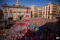 Members of the Castellers of Barcelona form their famous human tower called "castell" in Sant Jaume square in Barcelona, Spain, Sunday, Sept. 24, 2017.