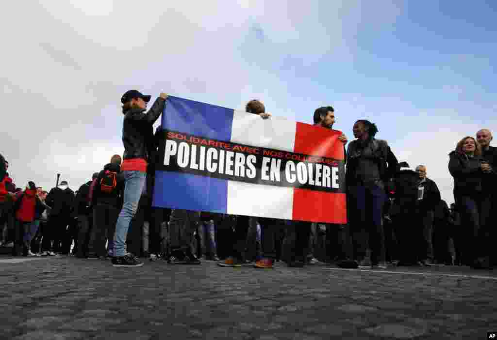 Police officers hold a French flag reading "Angry Policemen" during a demonstration in front of the National Assembly, in Paris, France, Oct. 26, 2016. 