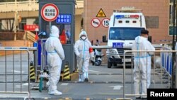 중국 시안 보건업무 관계자들이 20일 방역복을 입은 채 주거 지역 입구에 서 있다. 