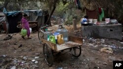 A woman carries buckets to fetch water from a public tap in a slum area in New Delhi, India, Jan. 17, 2016. The wealthiest 62 people own as much as half the world's population, as the super-rich have grown richer and the poor poorer, according to international charity Oxfam.