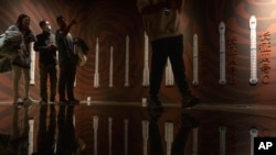 FILE - Visitors to an exhibition about China's space program stand near a depiction of the development of Chinese rockets, in Beijing on Dec. 28, 2023.