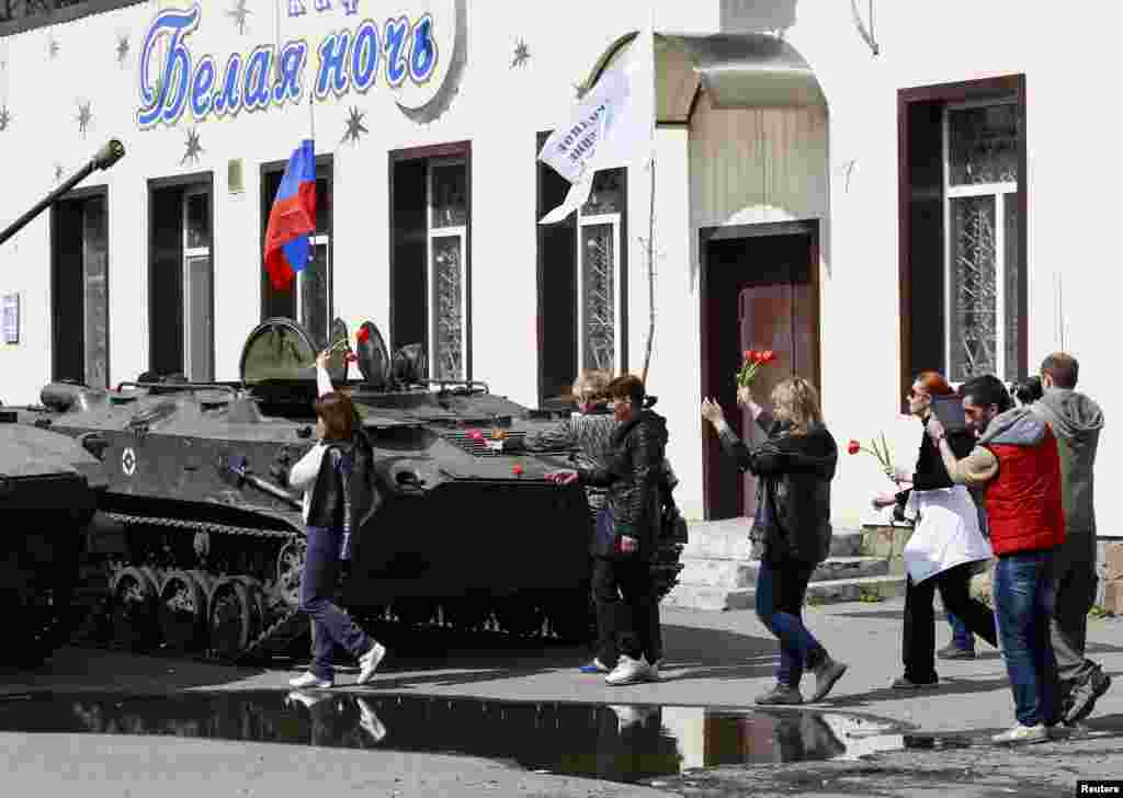 Local residents bring flowers to place them on armored personnel carriers in Slovyansk, Ukraine, April 16, 2014. 