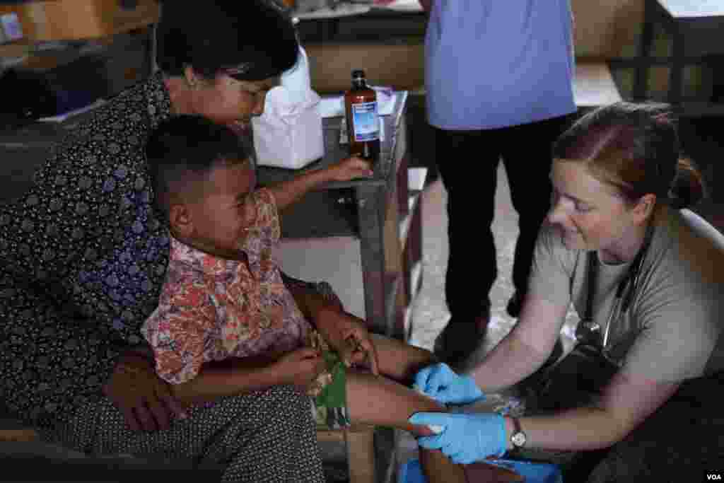 មន្ត្រី​កងទ័ពអាកាសសហរដ្ឋអាមេរិកព្យាបាលជើងដំបៅរបស់កុមារាមួយរូបនៅស្រុកកំពង់ត្រាច ខេត្តកំពត កាលពីថ្ងៃពុធ ទី១៥ ខែមិថុនា ឆ្នាំ២០១៦។