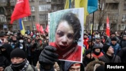 Para pengunjuk rasa Ukraina membawa foto wartawan Tetiana Chornovol dalam demonstrasi mereka di Kiev, 25/12/2013. Chornovol ditemukan dalam keadaan luka-luka di selokan beberapa jam setelah mempublikasikan artikel mengenai aset milik pejabat pemerintah. 