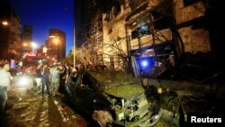 A wrecked vehicle is seen as policemen and civilians inspect the site of an explosion at Blom Bank in Beirut, Lebanon, June 12, 2016.