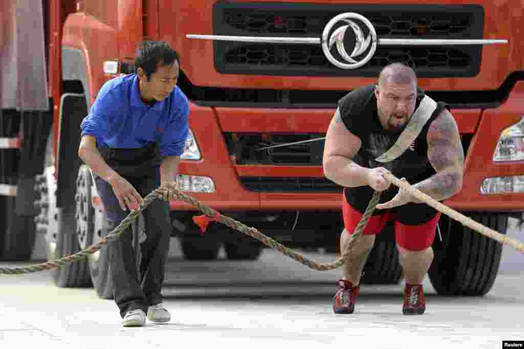 Peserta Inggris Kenneth Nowicki (kanan) menyeret truk selama lomba tahunan 'Hercules' di Xiangyang, provinsi Hubei, China.