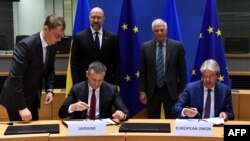 Ukrainian PM Denys Schyhal and EU Foreign Affairs and Security Policy Joseph Borrell look at Ukrainian Finance Minister Sergii Marchenko and EU commissioner for Economy Paolo Gentiloni signing an agreement during a EU-Ukraine Association Council meeting i