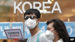 Sepasang warga Korea Selatan mengenakan masker sebagai tindak pencegahan terhadap virus Middle East Respiratory Syndrome (MERS) ketika berjalan-jalan di Myeongdong, salah satu lokasi perbelanjaan utama di Seoul, 15 Juni 2015. 