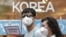 A couple wears masks as a precaution against the Middle East Respiratory Syndrome (MERS) virus as they walk in Myeongdong, one of Seoul's main shopping districts, June 15, 2015. 