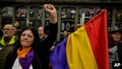FILE - A woman holds up her left fist beside to a Spanish Republican flag during a tribute 46 unidentified people killed during the Spanish Civil War, at San Jose cemetery, Pamplona, northern Spain, April 1, 2019.