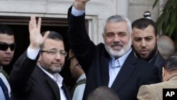 PM Palestina dari kelompok Hamas, Ismail Haniyeh (kanan) dan PM Mesir Hesham Kandil melambai kepada massa di kota Gaza. Kandil melakukan kunjungan singkat di Gaza (16/11).
