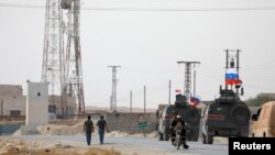 Russian and Syrian national flags flutter on military vehicles near Manbij, Syria, Oct. 15, 2019.