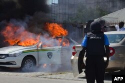 FILE - A Nigerian police officers watches a police vehicle as it goes up in flames following clashes with supporters of Islamic Movement of Nigeria (IMN) protesting against the imprisonment of their leader Ibrahim Zakzaky, in Abuja, on Oct. 30, 2018.
