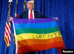 Then-Republican presidential nominee Donald Trump holds up a rainbow flag with "LGBTs for TRUMP" written on it at a campaign rally in Greeley, Colo., Oct. 30, 2016.
