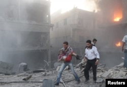 FILE - A man holds a girl, who survived what activists said was heavy shelling by forces loyal to Syria's President Bashar al-Assad in the Douma neighborhood of Damascus, June 16, 2015.