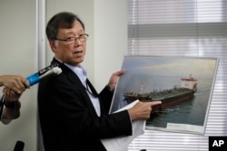 Yutaka Katada, president of Kokuka Sangyo Co., the Japanese company operating one of two oil tankers attacked near the Strait of Hormuz, shows a photo of the attacked oil tanker during a news conference Friday, June 14, 2019, in Tokyo. (AP Photo/Jae C. Ho