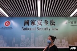 行人走过香港街头港版国安法的宣传牌。（2020年7月28日）