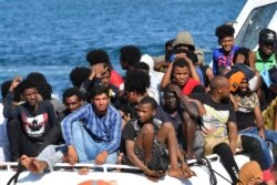 Migrants from Tunisia and Lybia arrive onboard an Italian Guardia Costiera (Coast Guard) boat on the Italian Pelagie Island of Lampedusa, Aug. 1, 2020.