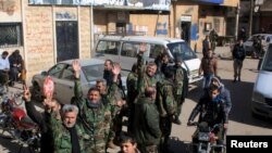 FILE - Fighters loyal to Syria's President Bashar al-Assad celebrate with residents of Nubul and al-Zahraa after breaking the siege of their towns in the northern Aleppo countryside, Syria, in this handout picture provided by SANA, Feb. 4, 2016.