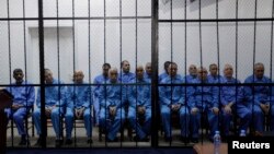 Officials of Moammar Gadhafi's government, including Abdullah al-Senussi (L), ex-spy chief in Moammar Gadhafi's government and Buzeid Dorda (2nd L), ex-intelligence chief, sit behind bars during a hearing at a courtroom in Tripoli, April 14, 2014.