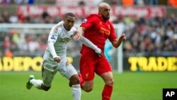 Jonathan de Guzman, kiri, dari Klub Swansea berusaha merebut bola dari Jose Enrique dari klub Liverpool dalam pertandingan Liga Premier hari Minggu (25/11).