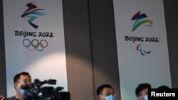 Reporters are seen in front of the Beijing 2022 Winter Olympic and Paralympic Games signs during a news conference on the construction progress of the sports event venues, at the headquarters of the Beijing Organising Committee, in Beijing, China July 30…