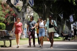 Pedestrians walk on a boulevard as Israel rescinds the mandatory wearing of face masks outdoors in the latest return to relative normality, boosted by a mass-vaccination campaign against the coronavirus pandemic, in Tel Aviv, Israel, April 18, 2021.
