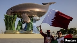 Fans dari timnas sepak bola Meksiko dan Qatar berfoto di depan instalasi dugong di Doha, Qatar, pada 16 November 2022. (Foto: Reuters/Marko Djurica)