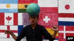 FILE - In this picture taken Nov. 7, 2022, a boy plays soccer in front of a wall mural ahead of the Qatar 2022 FIFA World Cup football tournament, along a street in Karachi. 