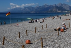 A man sits in an area marked by cordons of ropes and wooden stakes to enforce social distancing measures on the Konyaalti beach, amid the COVID-19 outbreak, in the southern resort city of Antalya, Turkey, June 19, 2020.