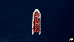 FILE - Refugees and migrants wait to be rescued by members of the Spanish NGO Proactiva Open Arms, after leaving Libya trying to reach European soil aboard an overcrowded rubber boat, north of Libyan coast, May 6, 2018.