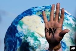 A hand of a protester reads "pay" amid calls for reparations for loss and damage at the COP27 U.N. Climate Summit, in Sharm el-Sheikh, Egypt, Nov. 18, 2022. (AP Photo/Peter Dejong)