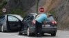 FILE - A driver removes a sticker covering the national markings on his car plates at the Jarinje border crossing, Kosovo, Sept. 1, 2022. 