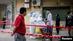 在新冠病毒疫情爆发最严重的湖北省武汉市，医护人员身穿防护服，在小区内对居民进行核酸检测（2020年5月15日）。