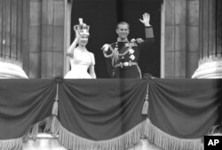 Ratu Inggris Elizabeth II dan Pangeran Philip, Duke of Edinburgh, melambaikan tangan mereka kepada para pendukungnya dari balkon di Istana Buckingham, setelah penobatannya di Westminster Abbey. London, Juni. 2, 1953. (AP Photo/Imam)