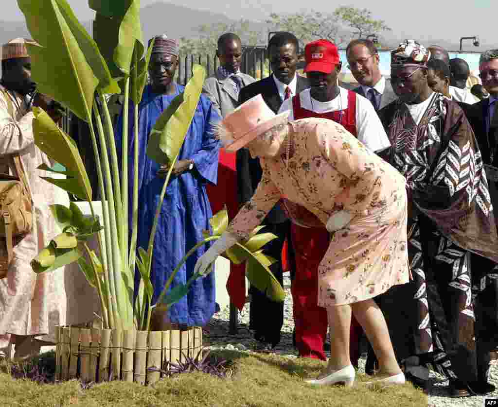 Queen Elizabeth II, flanked by Nigerian President Olusegun Obasanjo (R), plants a banana tree 04 December 2003 as they visit the Millenium Park in Abuja, Nigeria.