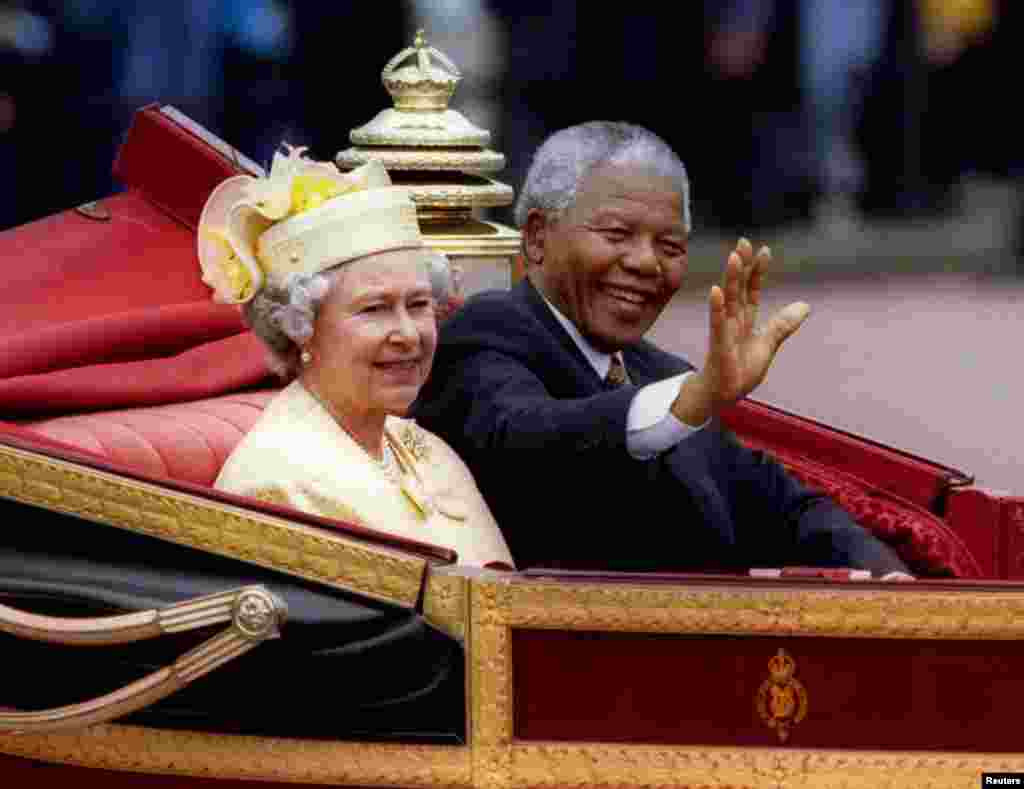 South African President Nelson Mandela is accompanied by Queen Elizabeth II in a carriage ride to a Buckingham Palace lunch on the first day of his state visit to Britain, July 9, 1996.