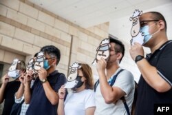 FILE - Supporters of a pro-democracy union pose with illustrations of sheep outside West Kowloon Court in Hong Kong on July 23, 2021, where members of the union face charges of sedition for publishing children's books that allegedly try to explain the city's democracy movement using illustrations of sheep.