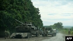 Tentara Ukraina memeriksa kendaraan militer Rusia yang ditinggalkan di sebuah trailer selama pertempuran di Kharkif, Ukraina Minggu 11 September 2022.