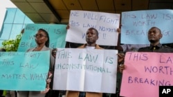 FILE - Digital activists hold placards as they demonstrate after submitting a legal petition against controversial new legislation criminalizing some internet activity, at the Constitutional Court in Kampala, Uganda, Oct. 17, 2022.