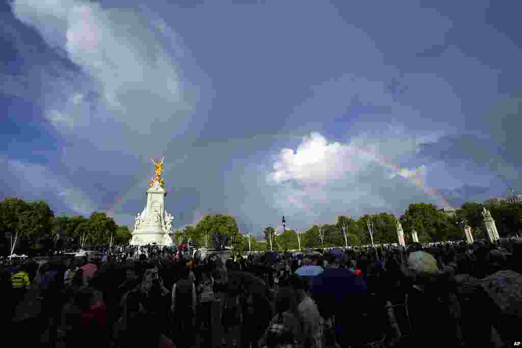 People gather outside Buckingham Palace in London as a double rainbow appears, Sept. 8, 2022.