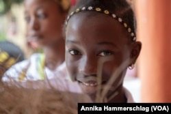 Alia Bindia, 12, holds up a basket of fonio at Senegal’s annual day of fonio in Kedougou, Senegal, Nov. 15, 2022. (Annika Hammerschlag/VOA)