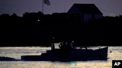 A man on a lobster fishing boat drinks his coffee while heading out to sea before dawn, Thursday, Sept. 8, 2022, off of Kennebunkport, Maine. (AP Phot6o/Robert F. Bukaty)