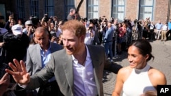 Britain's Prince Harry, left, and Meghan, Duchess of Sussex, meet people after a visit at the town hall in Duesseldorf, Germany, Sept. 6, 2022.